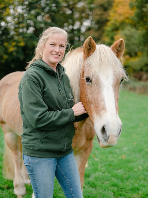 Maike medewerker van Stichting De Paardenkamp naast een paard.